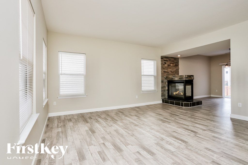 A spacious room with a fireplace and wooden flooring.