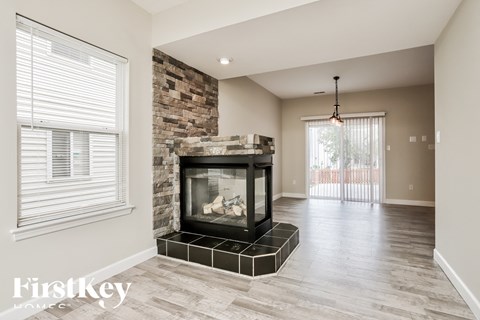 A modern living room with a stone fireplace and a chandelier.