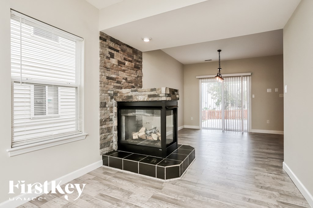 A modern living room with a stone fireplace and a chandelier.