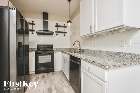 A kitchen with a black refrigerator and white cabinets.