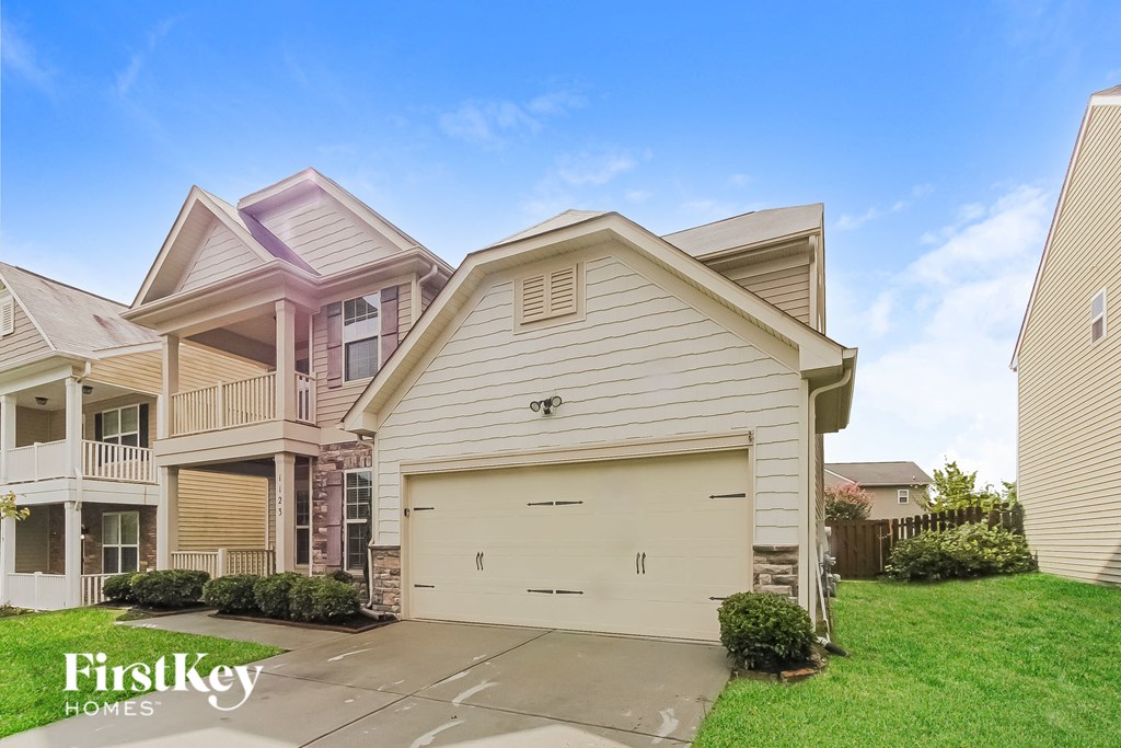 a white house with a garage door in front of a green lawn
