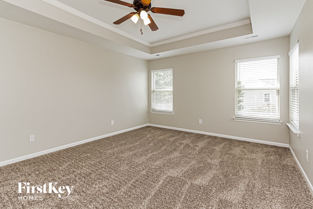 an empty living room with carpet and a ceiling fan