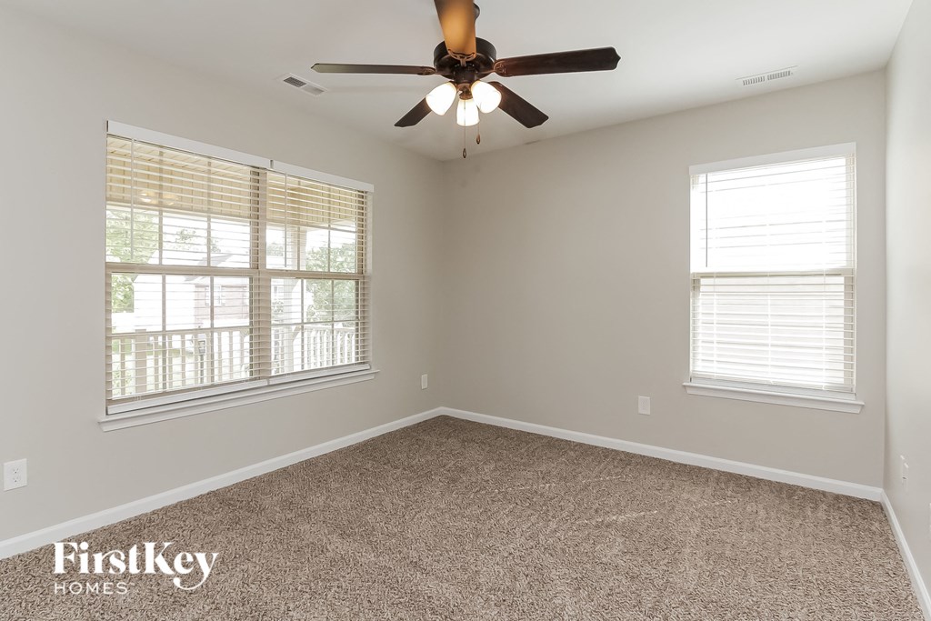 an empty room with a ceiling fan and two windows