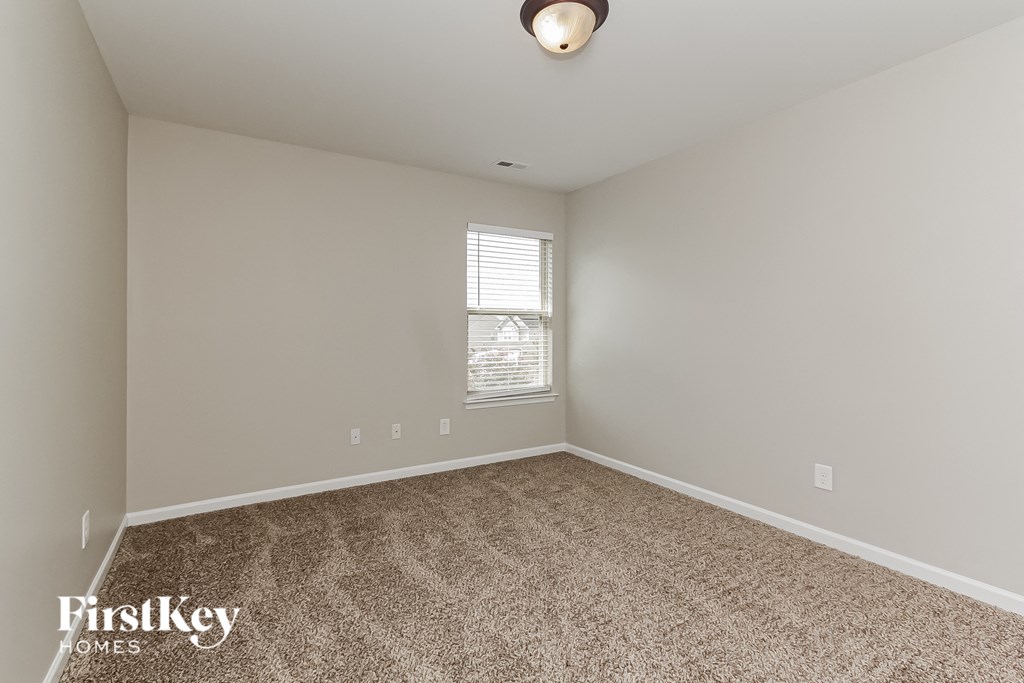 the spacious living room with carpeting and a window