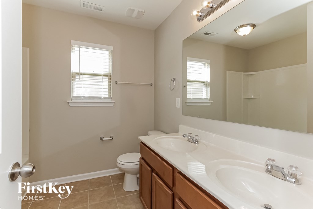 a bathroom with two sinks and a toilet and a large mirror