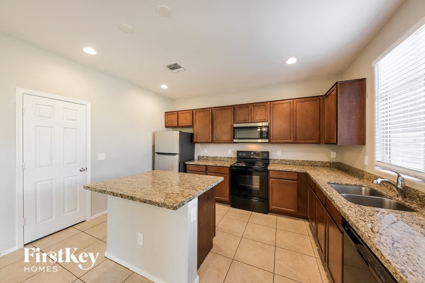 A kitchen with a granite countertop and wooden cabinets.