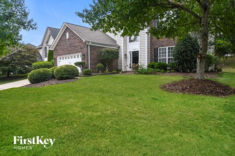 a home with a lawn and a tree in front of it