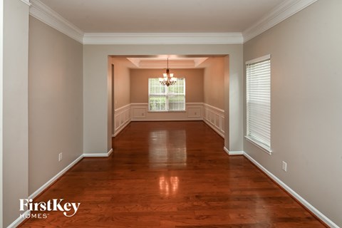 an empty dining room with wood floors and a chandelier