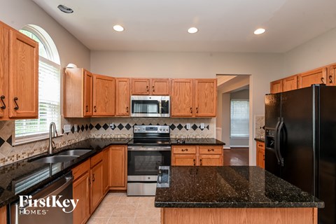 a kitchen with black granite counter tops and wooden cabinets