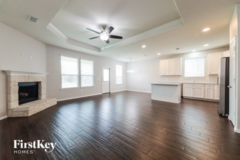 A spacious living room with wood flooring and a fireplace.