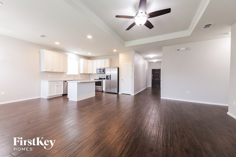 A spacious kitchen with wooden floors and a ceiling fan.