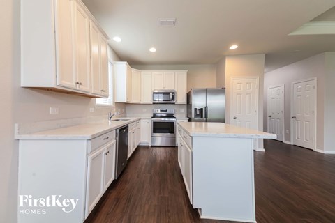 A kitchen with white cabinets and a wooden floor.