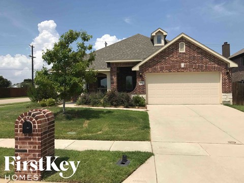 A brick house with a garage and a brick pillar with a mailbox on it.