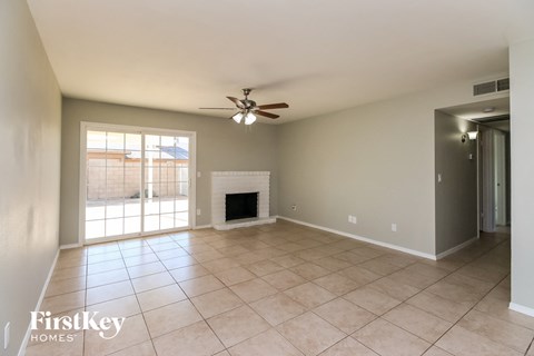an empty living room with a fireplace and a ceiling fan