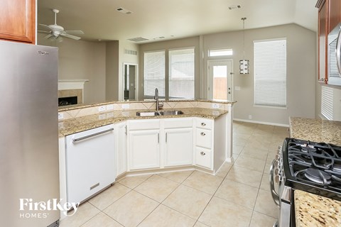 a kitchen with white cabinets and granite counter tops and a stove and sink