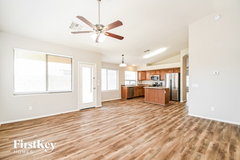 A spacious room with a fan and wooden flooring.