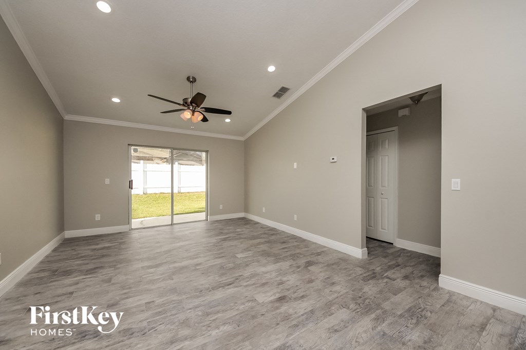the spacious living room with a ceiling fan and a door to the patio
