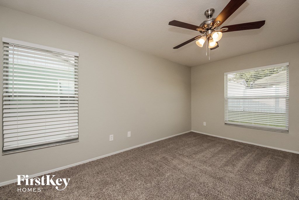 the living room has a ceiling fan and two windows