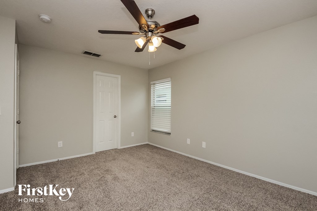 the living room is spacious and has a ceiling fan