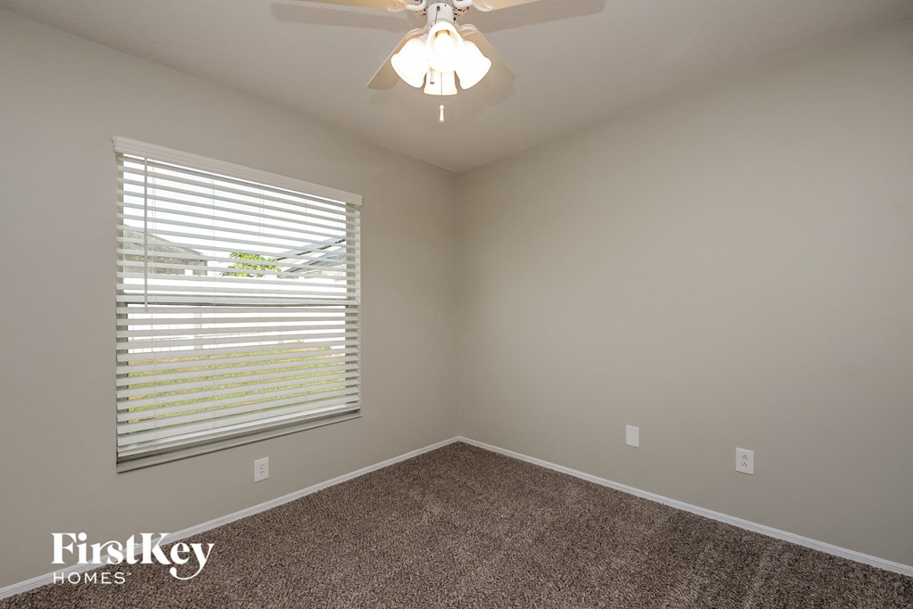 the second bedroom has a large window and a ceiling fan