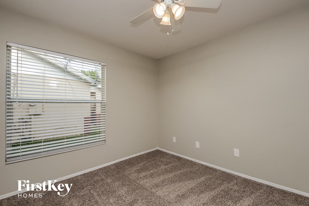 a bedroom with a large window and a ceiling fan