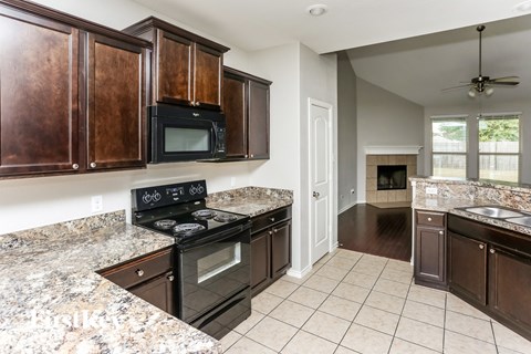 a kitchen with wood cabinets and black appliances and granite counter tops
