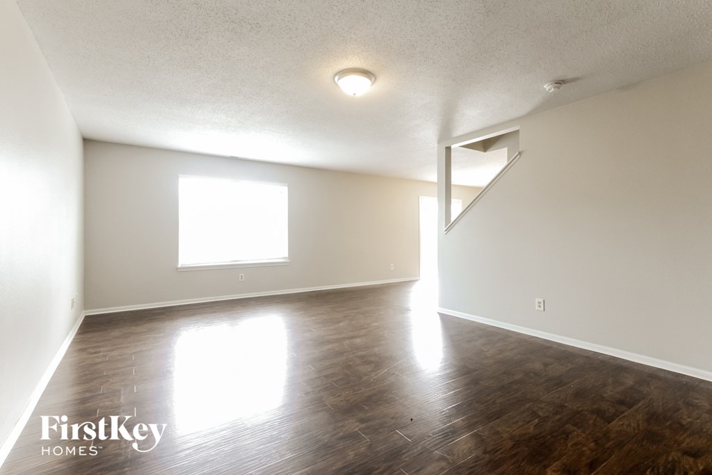 an empty living room with wood floors and white walls