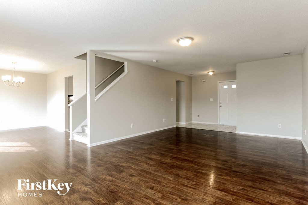an empty living room with a hard wood floor and white walls