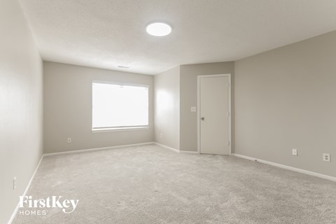 a spacious living room with white carpet and a window