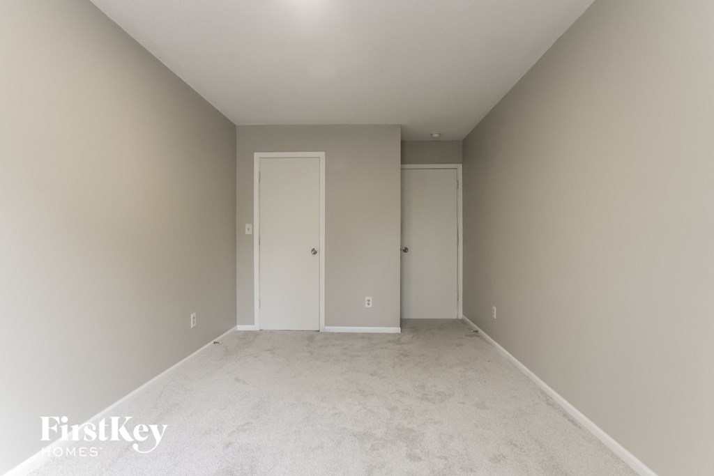 a empty bedroom with white carpet and white doors