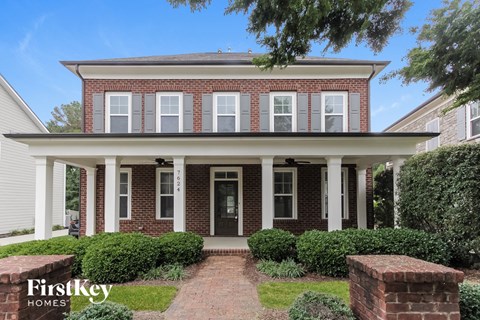 a brick house with white pillars and a walkway