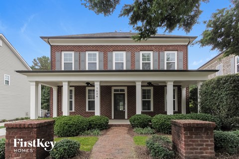 a brick house with white pillars and a walkway