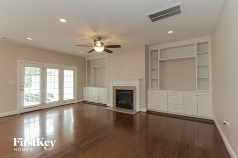 an empty living room with a ceiling fan and a fireplace