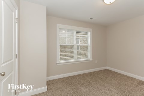 a bedroom with a large window and a carpeted floor
