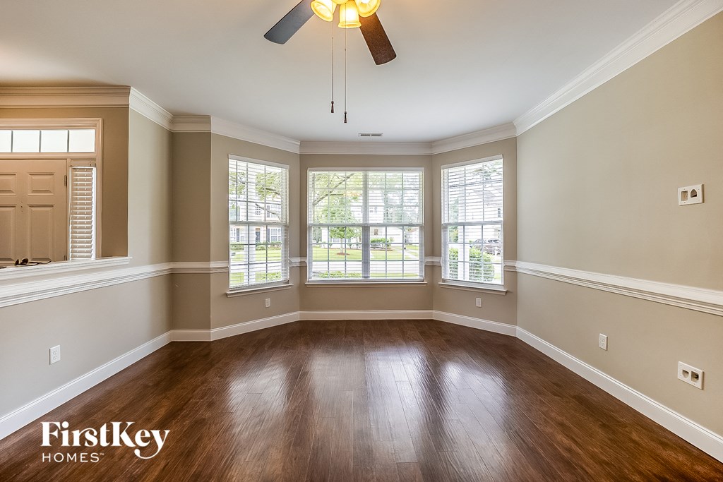 A spacious room with wooden floors and a ceiling fan.