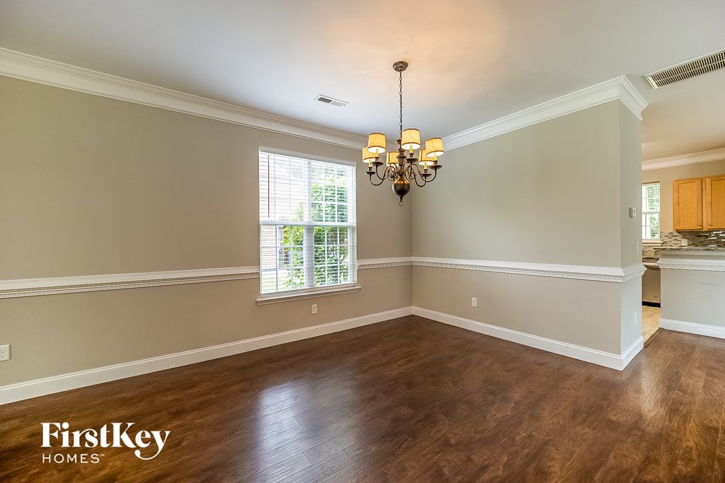 A room with wooden floors and a chandelier hanging from the ceiling.