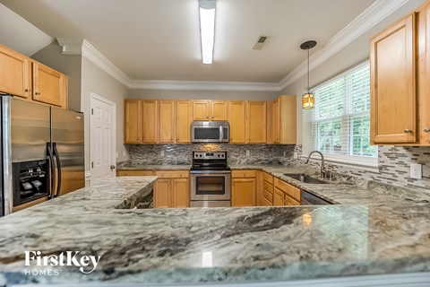 A kitchen with granite countertops and wooden cabinets.
