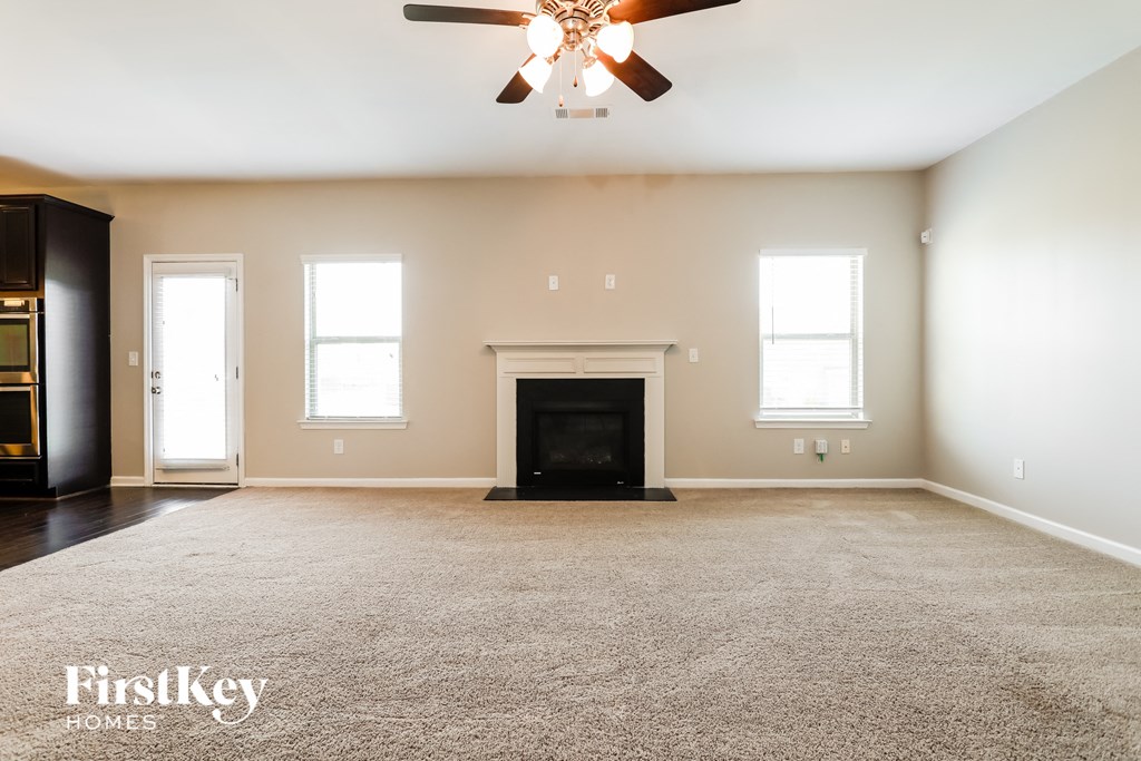 A spacious living room with a fireplace and a ceiling fan.