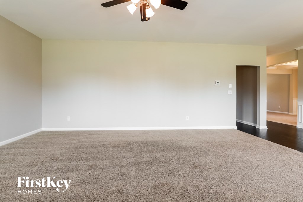 A room with a carpet floor and a ceiling fan.