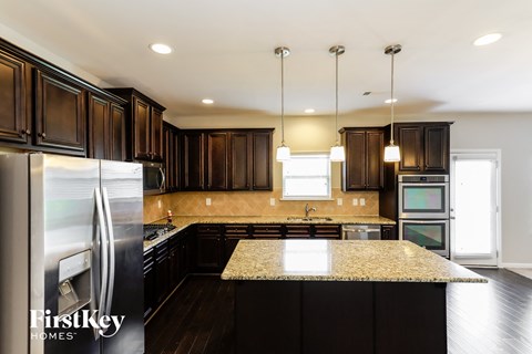 A kitchen with dark wood cabinets and a granite countertop.