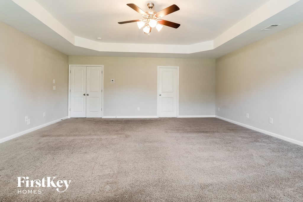 A spacious room with a ceiling fan and two doors.