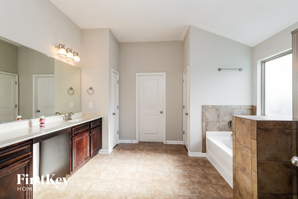 A bathroom with a sink, mirror, and bathtub.