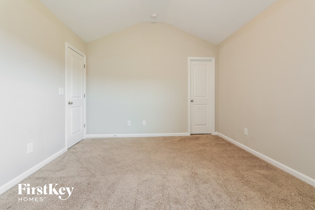 A carpeted room with two doors and a FirstKey Homes logo.
