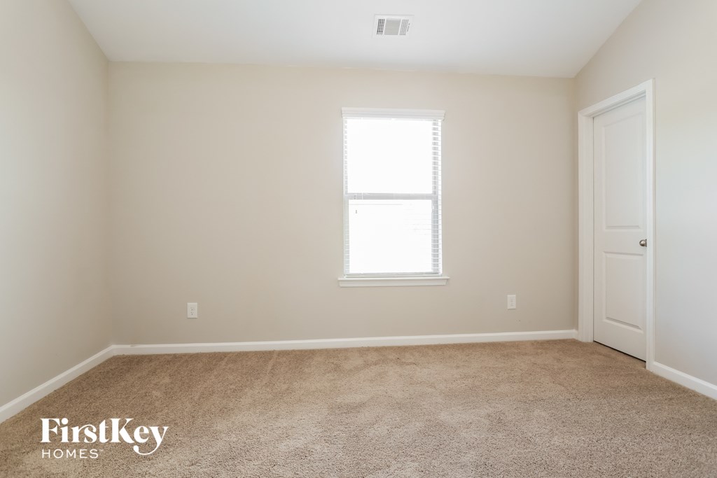 A room with a carpeted floor, a window, and a door.