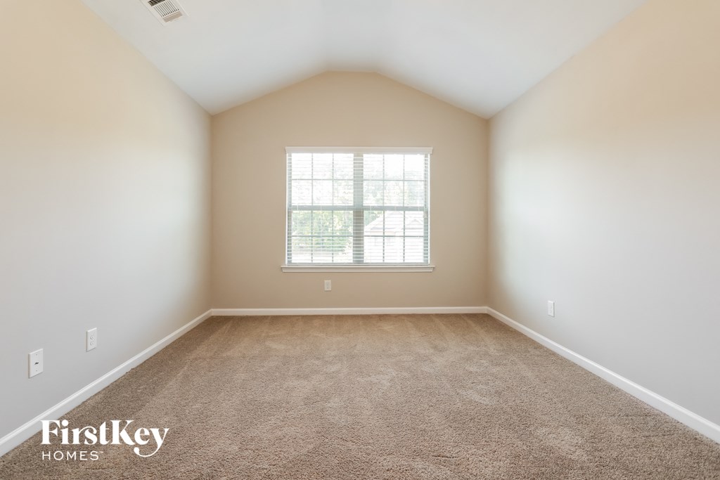 A room with a carpeted floor and a window with blinds.
