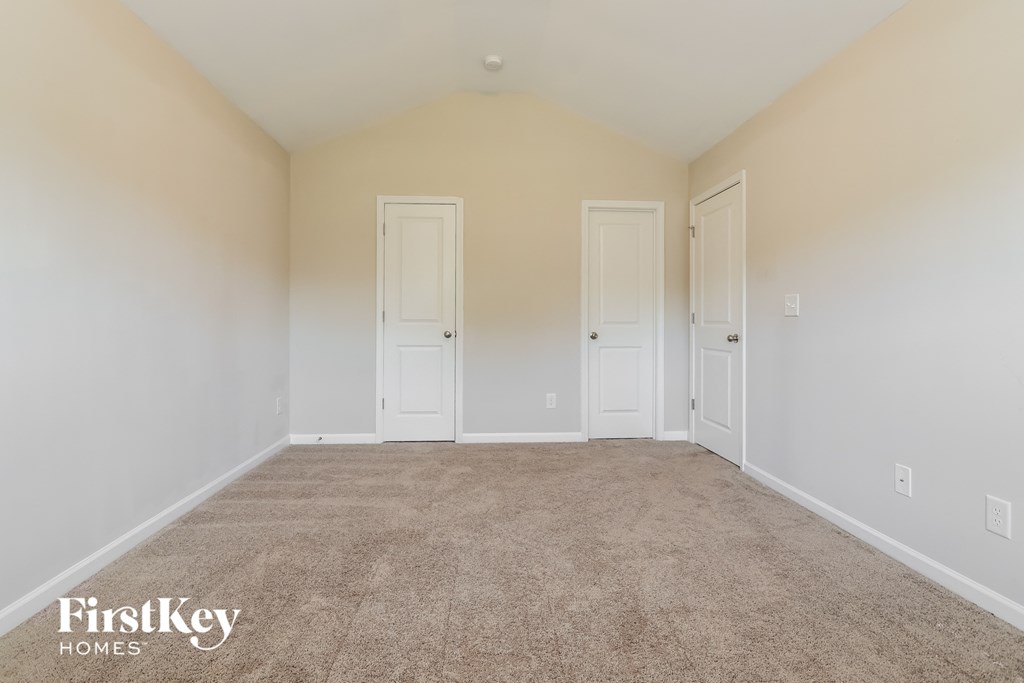 A carpeted room with three doors and a FirstKey Homes logo.