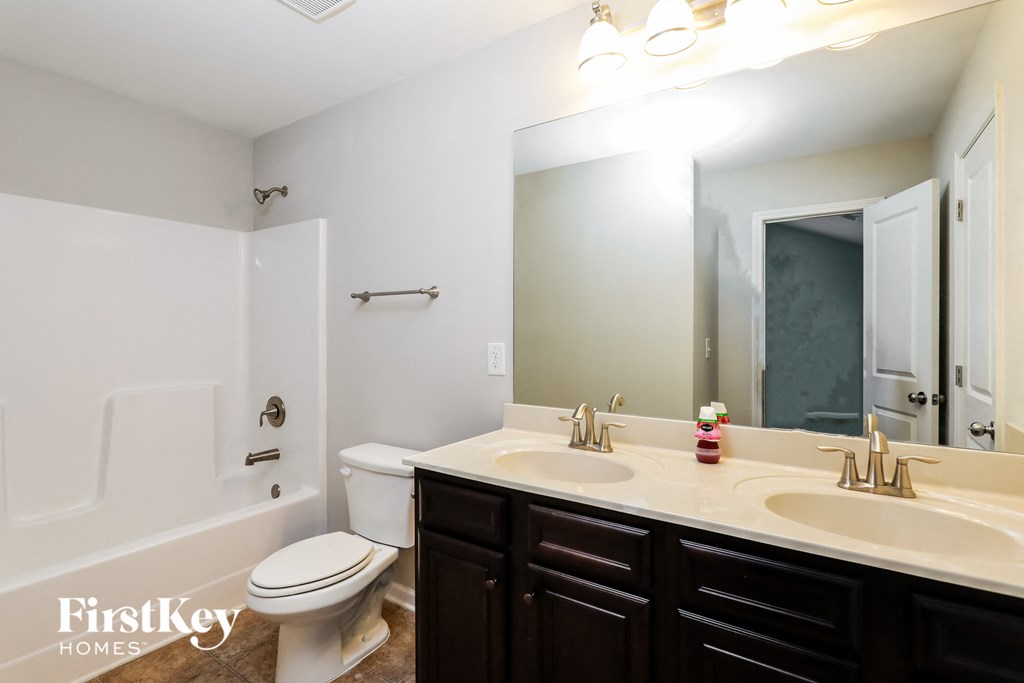 A bathroom with a toilet, sink, and mirror.