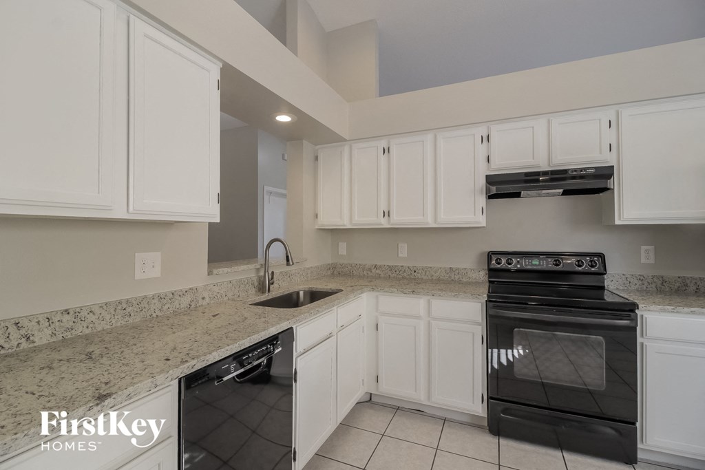 A kitchen with white cabinets and a black oven.