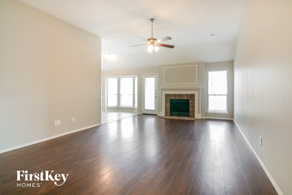 an empty living room with a ceiling fan and a fireplace