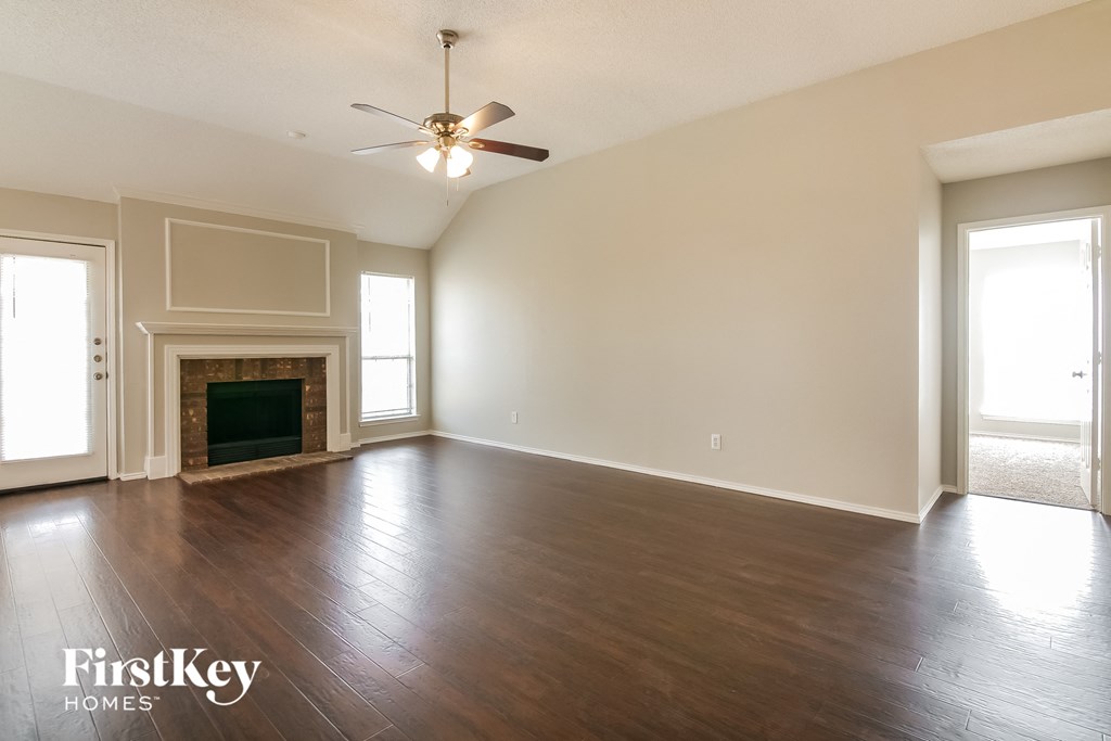 an empty living room with a ceiling fan and a fireplace